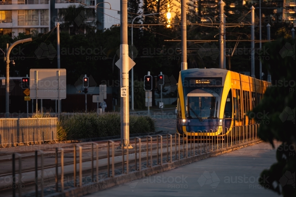 The G:link light rail tram on the Gold Coast passing through station with Surfers Paradise buildings - Australian Stock Image