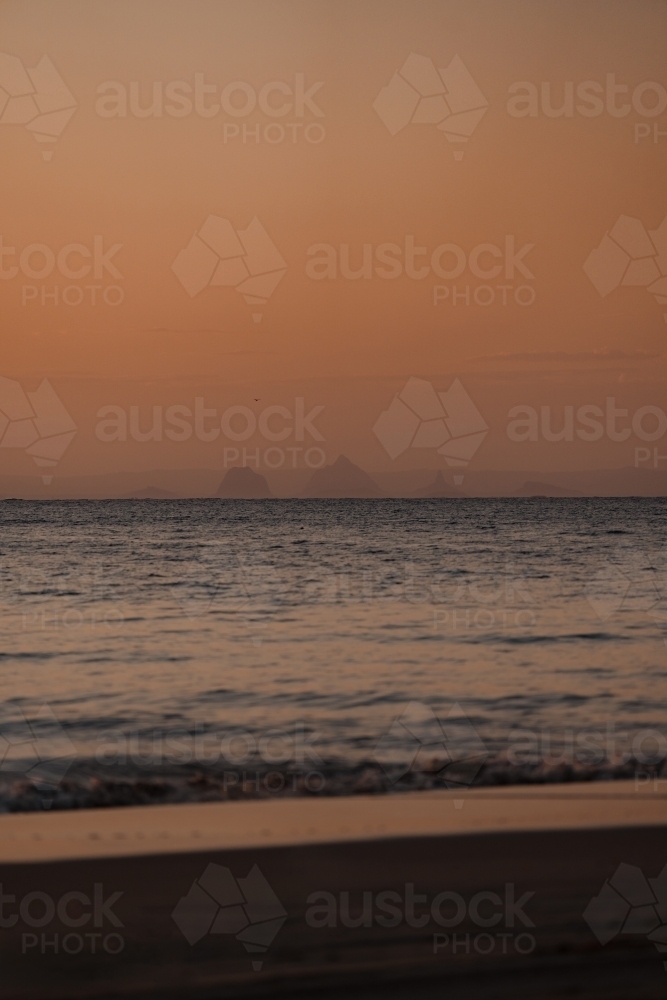 The Glasshouse Mountains visible from Moreton Island at sunset - Australian Stock Image