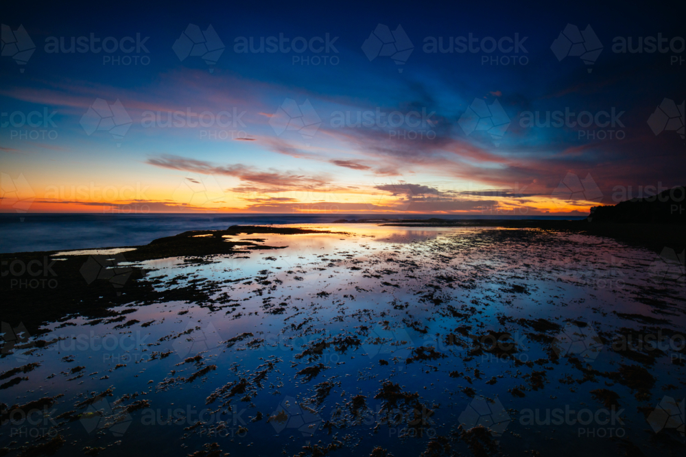 The idyllic Pearses Beach and headland around Pirates Bay Cove on a hot summer's evening - Australian Stock Image