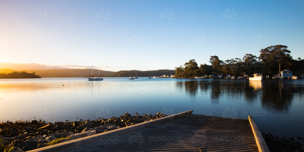 The idyllic setting across Wagonga Inlet at sunset in Narooma, NSW, Australia - Australian Stock Image