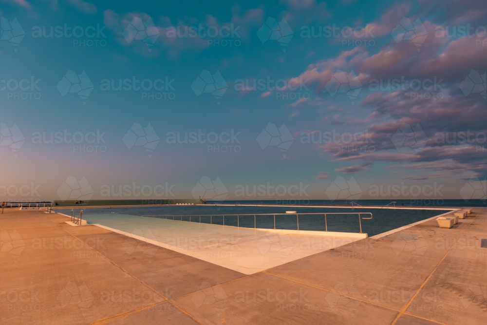 The Newcastle Ocean Baths at dusk with pink and purple fairy floss sky - Australian Stock Image