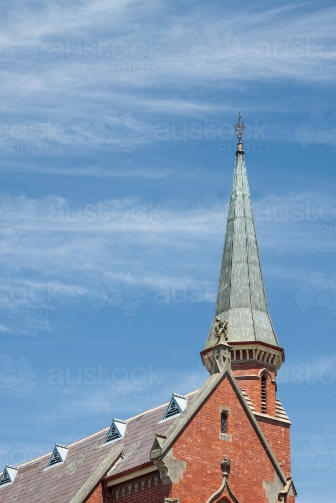 The pointed roof and steeple of a church set against a blue sky - Australian Stock Image