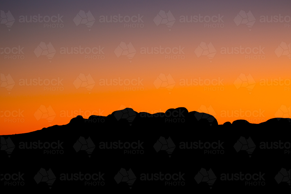 The silhouette of the boulders of the Olgas at sunset on a clear winter's evening in NT - Australian Stock Image