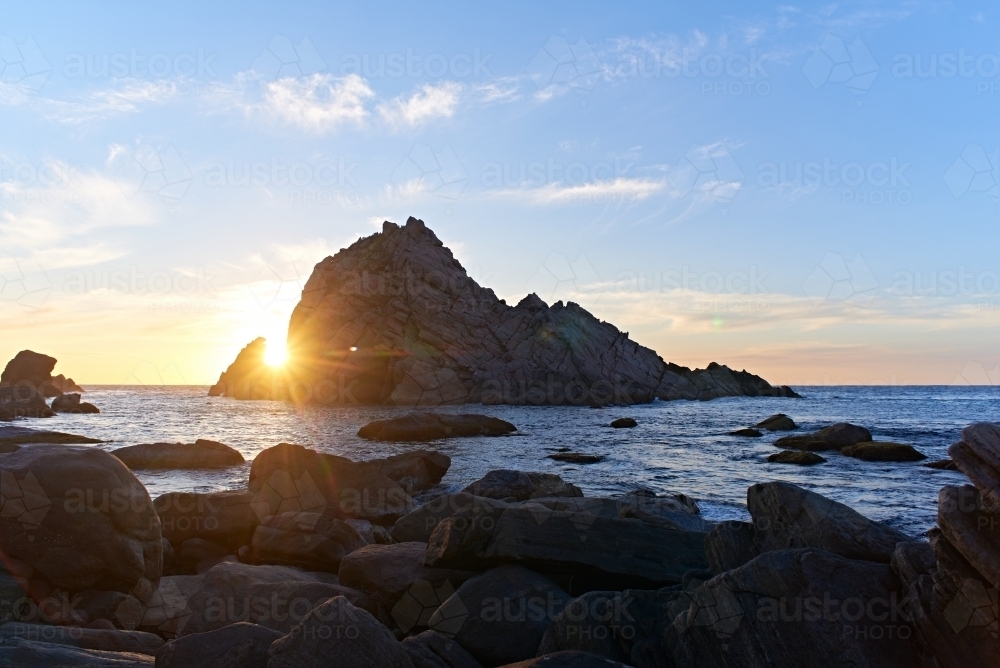 The sun setting behind Sugarloaf Rock, near Dunsborough, Western Australia. - Australian Stock Image