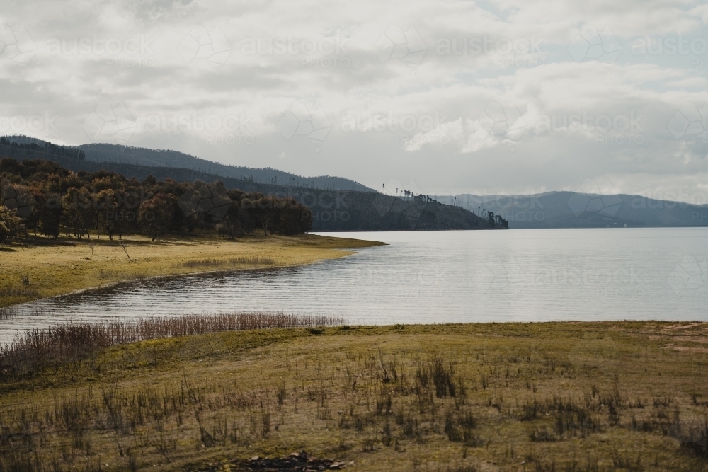 The water's edge with mountains in the background at Blowering Reservoir - Australian Stock Image