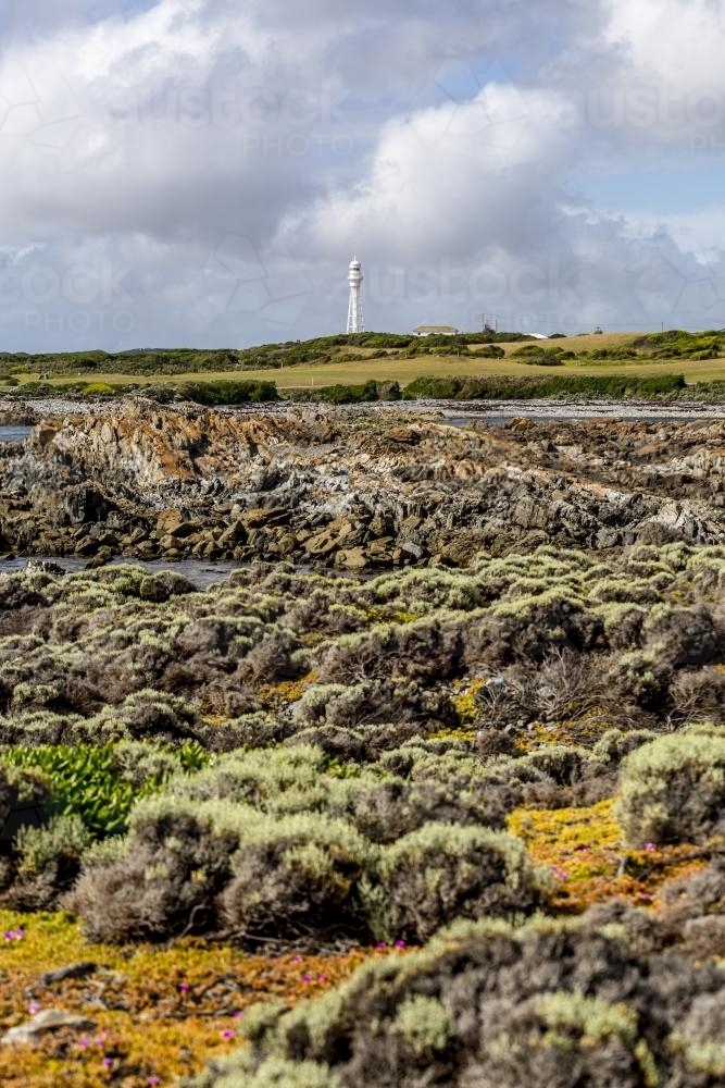 The white Currie Lighthouse rises above the colourful shoreline as clouds roll in - Australian Stock Image