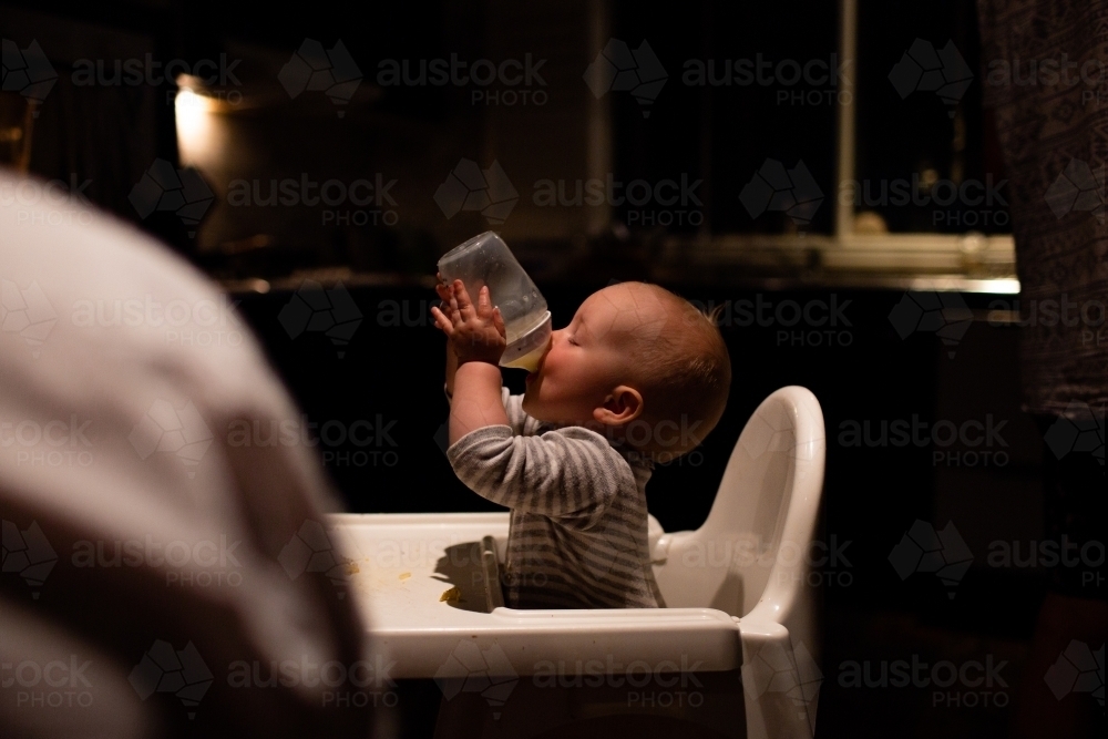 Thirsty baby drinking bottle - Australian Stock Image