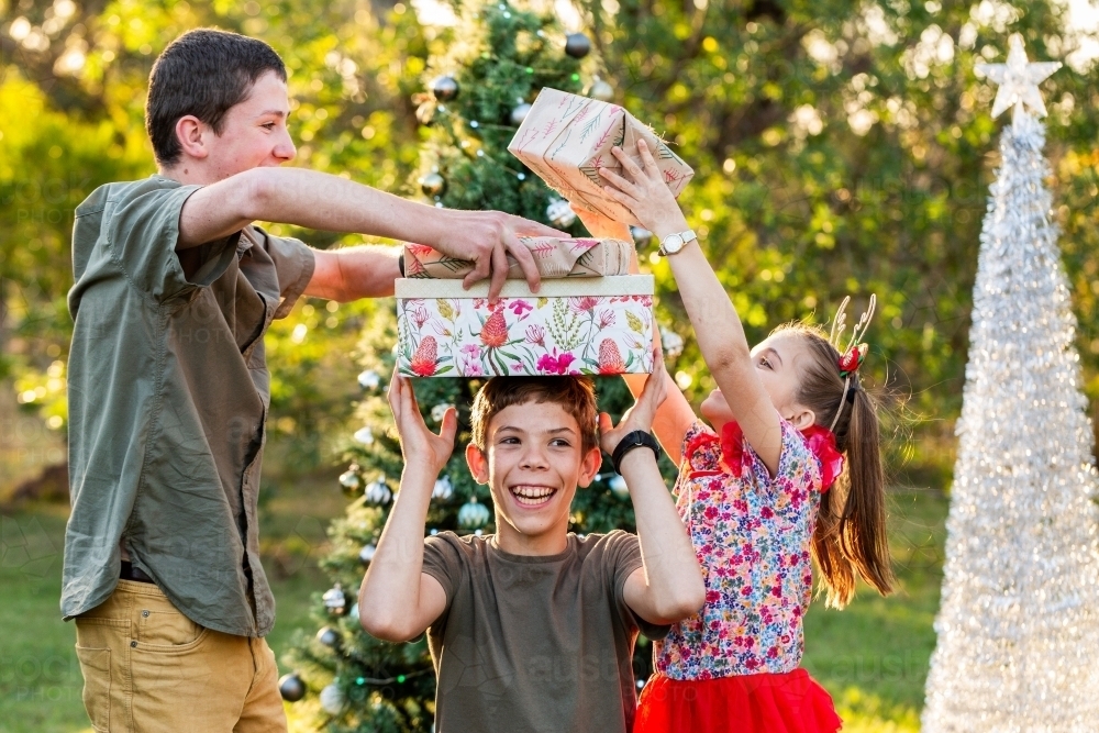 Three Aussie kids being silly with Christmas gifts in rural Australia - Australian Stock Image