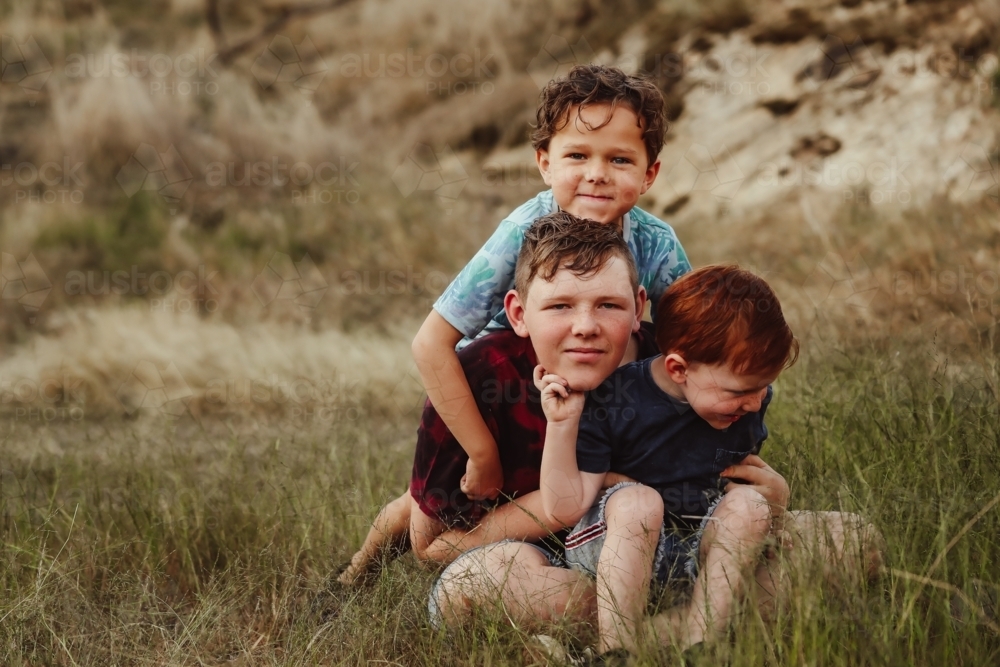 Three brothers sitting together on a rock in the Australian bush - Australian Stock Image