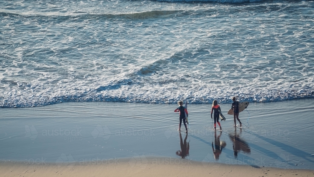 Three female surfers entering the ocean - Australian Stock Image