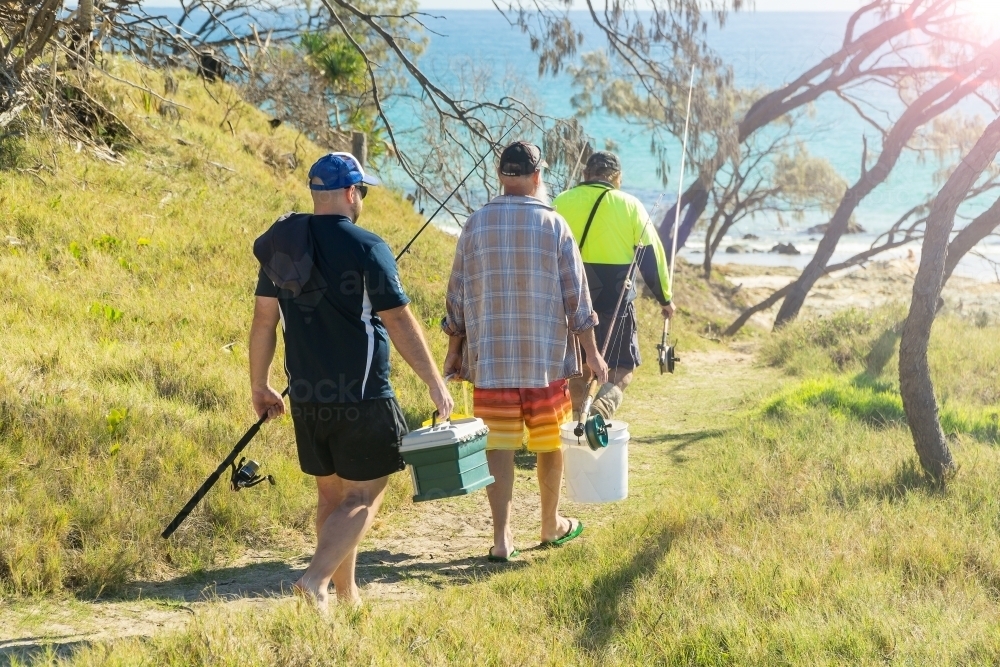 Image of Three fishermen walking down a track to the beach - Austockphoto