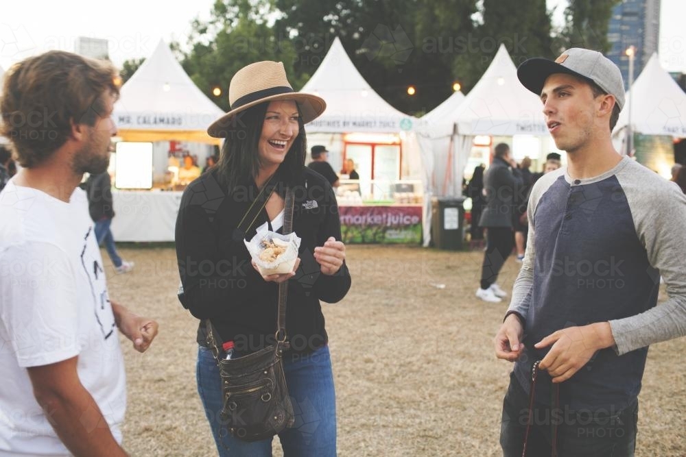 Three friends laughing together at a carnival - Australian Stock Image