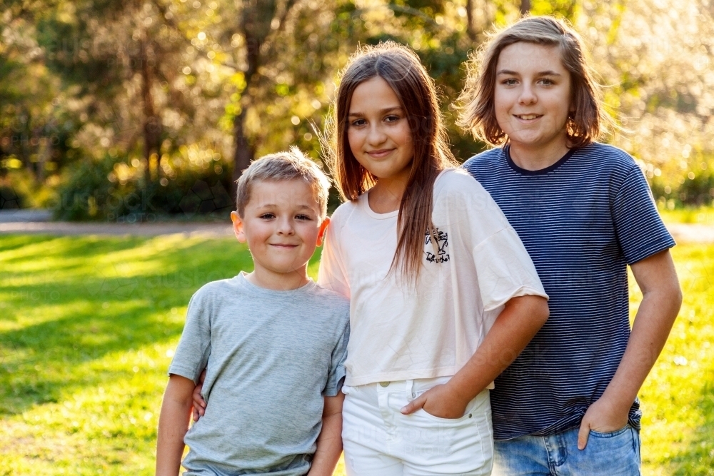 Image of Three kids standing together in park - Austockphoto