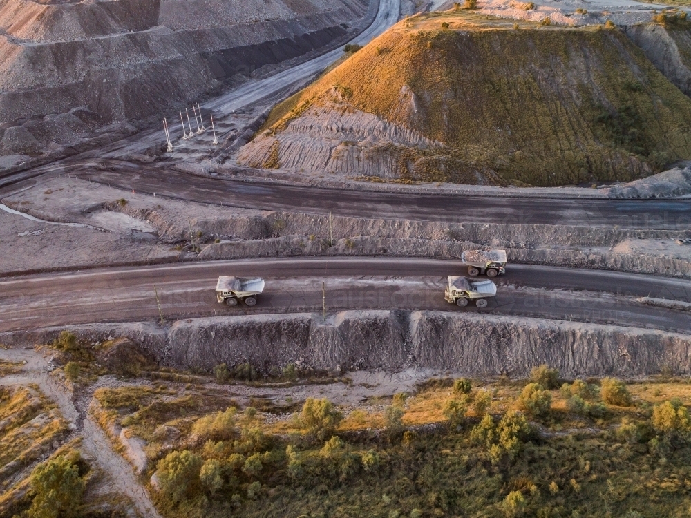 Three mining dump trucks hauling coal in mine site in Hunter Valley - Australian Stock Image