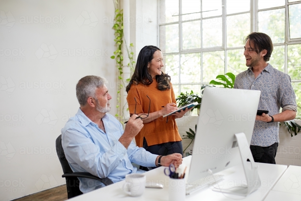 Three professional business people, sharing ideas in a studio office - Australian Stock Image