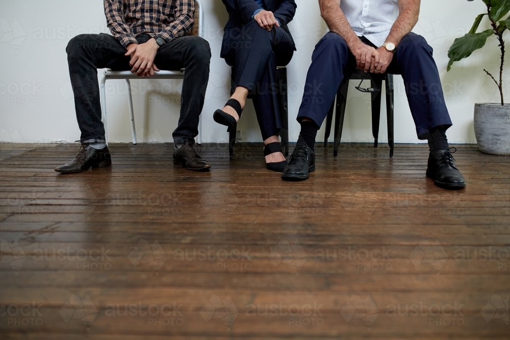 Three professional business people sitting in a row in a studio - Australian Stock Image