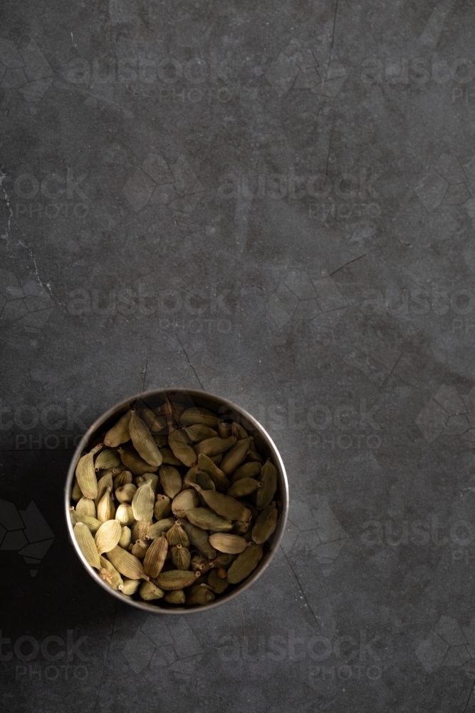 Tin of cardamon pods on dark marble background - Australian Stock Image