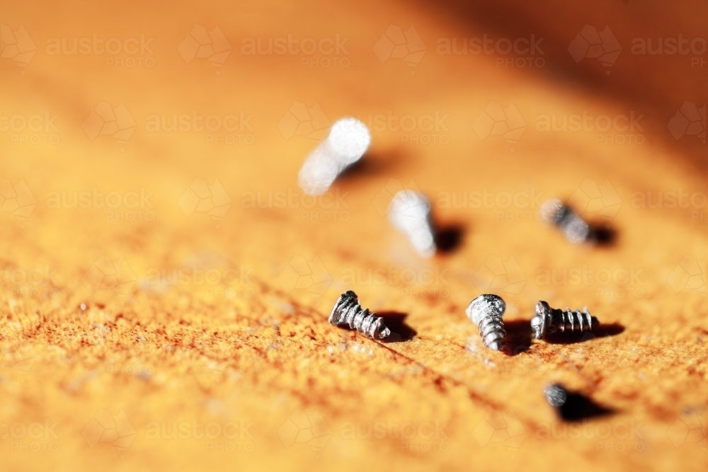 Tiny screws on wooden tabletop - Australian Stock Image