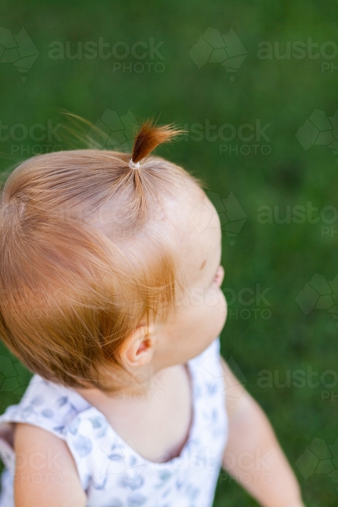 Toddler outside in nature with hair up in fountain hairstyle - Australian Stock Image