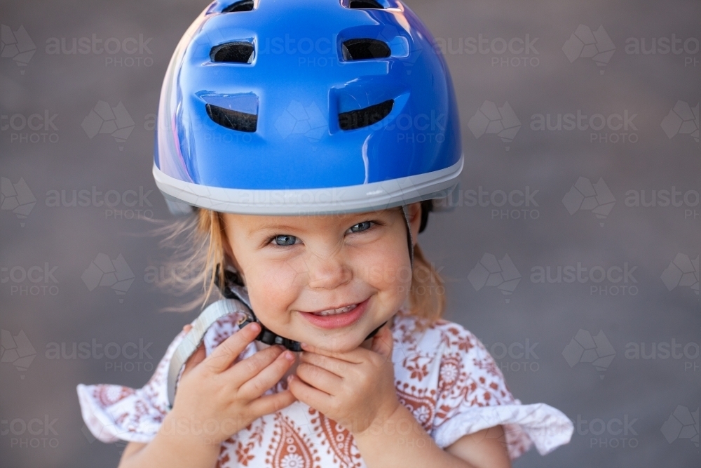 Toddler touching helmet buckle ready for riding bike outside - Australian Stock Image