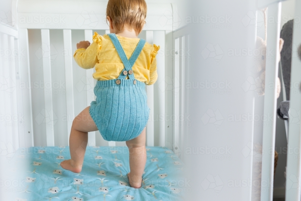 Toddler walking in cot - Australian Stock Image