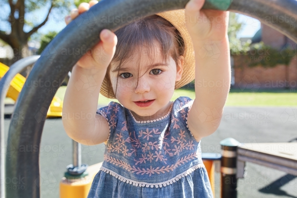 Toddler wearing hat looking at camera in park - Australian Stock Image