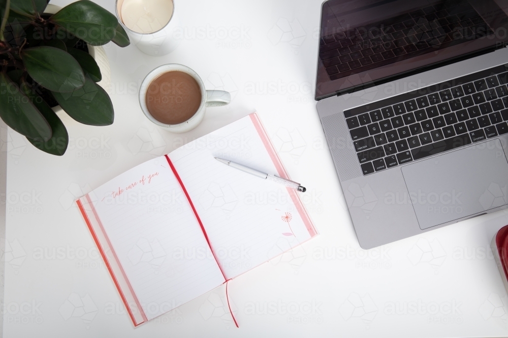 top down desk view of laptop, mug of hot chocolate and journal - Australian Stock Image