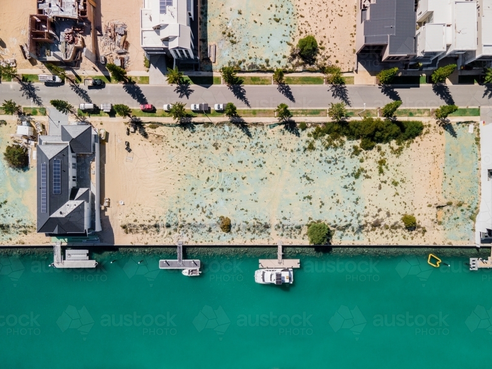 top shot of a beach with docked boats, trees, buildings and trees on a sunny day - Australian Stock Image