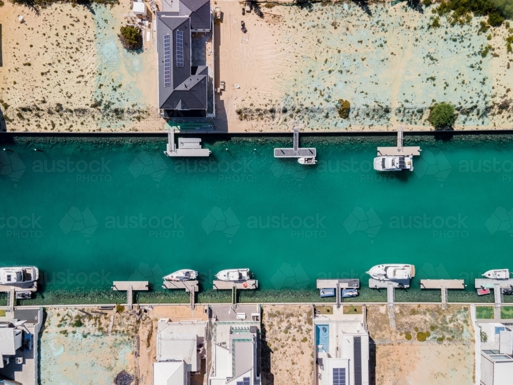 top shot of a beach with docked boats, trees, house and trees on a sunny day - Australian Stock Image