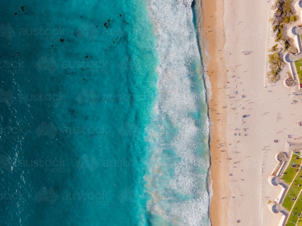 top shot of a beach with waves. people on white sand shoreline and green grass. on a sunny day - Australian Stock Image