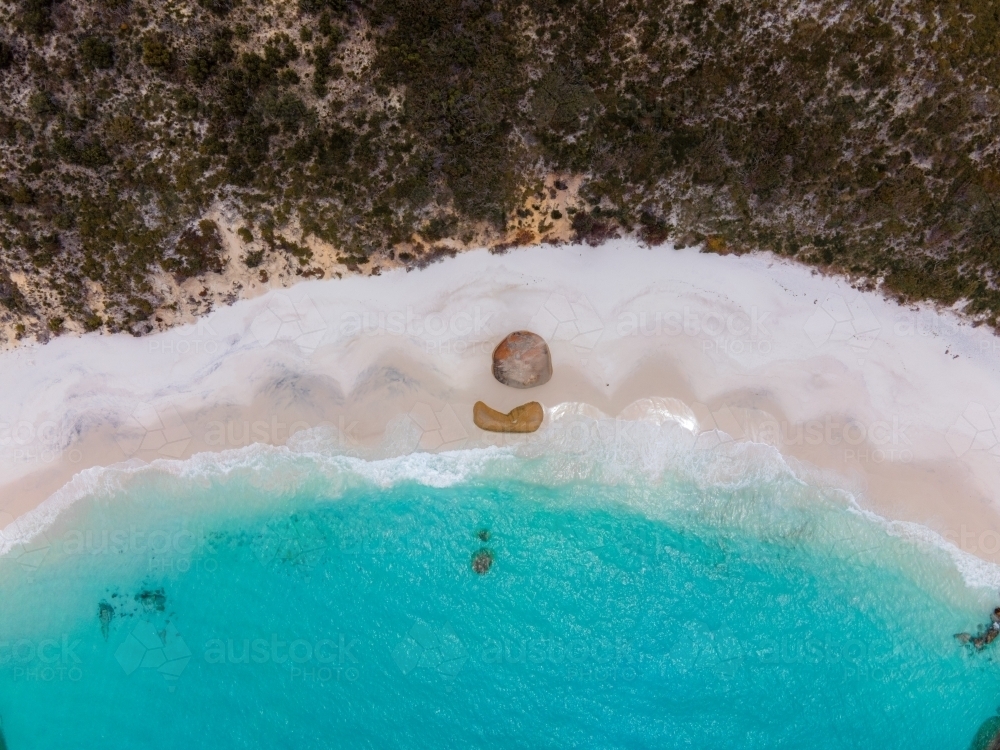 top shot of a beach with white sand shoreline, waves, bushes, trees and rocks - Australian Stock Image