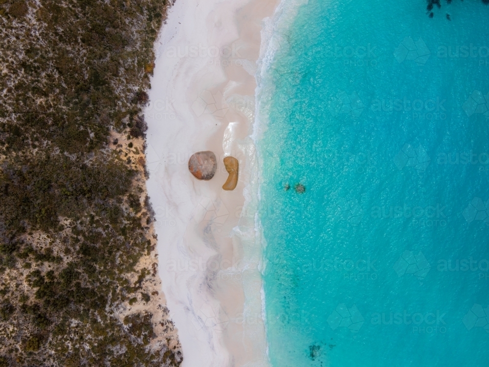 top shot of a beach with white sand shoreline, waves, bushes, trees and rocks - Australian Stock Image