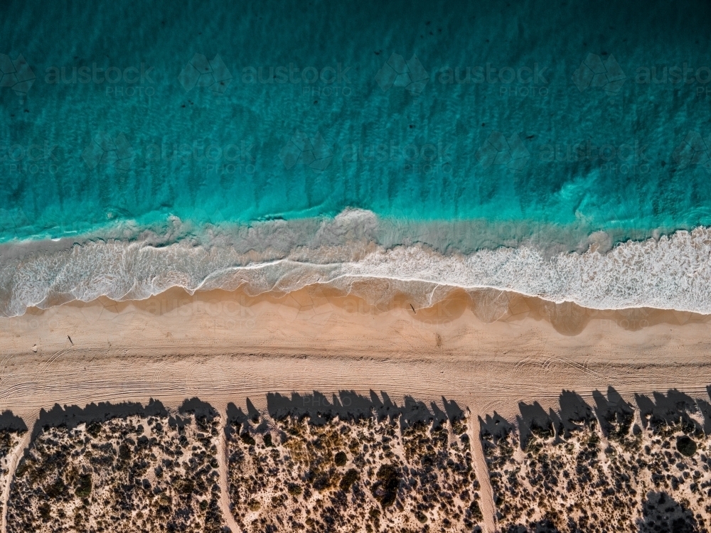 top shot of a shoreline waves with white sand, grass and ocean water - Australian Stock Image