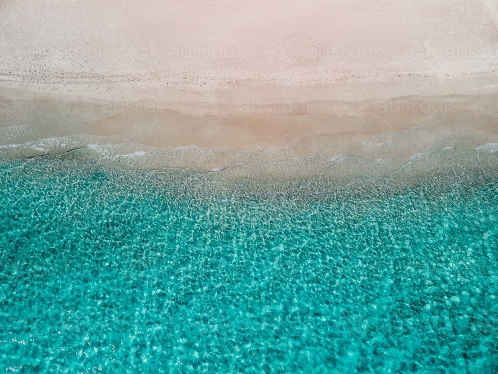 top shot of a white sand beach with small waves on a sunny day - Australian Stock Image