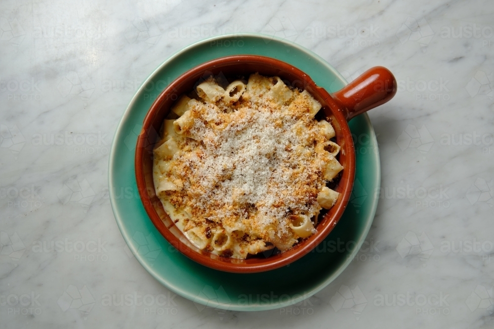 Top shot of guanciale and four cheese truffle mac in a red mug on a green plate - Australian Stock Image