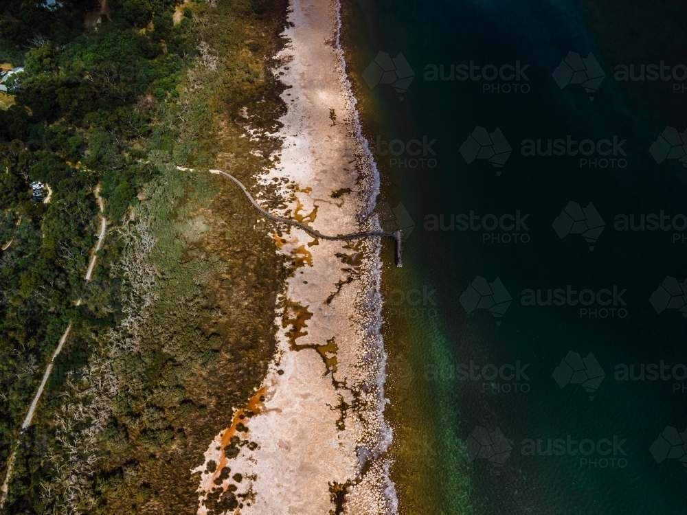 top view shot of a beach walkway with bushes, trees and waves on a sunny day - Australian Stock Image