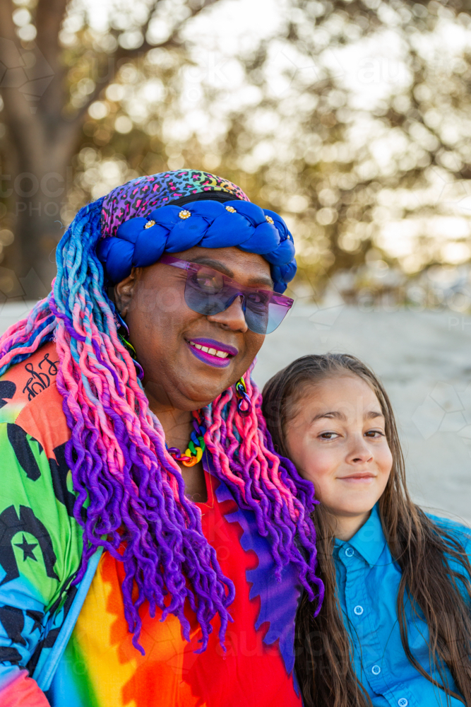 Torres Strait Islander nine year old boy with long hair sitting beside grandmother on the beach - Australian Stock Image
