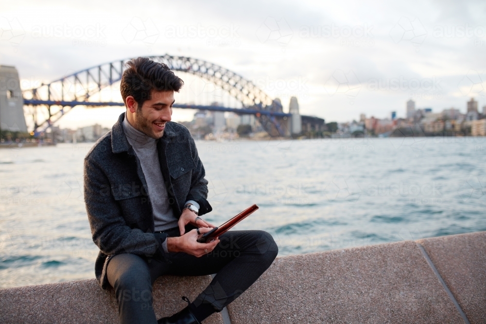 Tourist checking phone with the Sydney Harbour Bridge in background - Australian Stock Image
