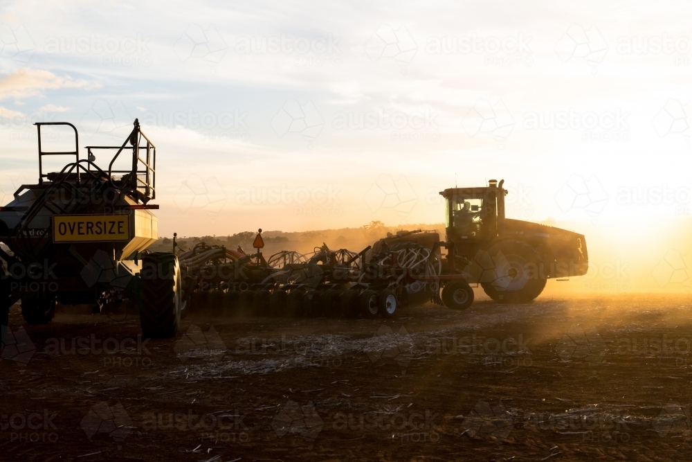 Tractor and air seeder planting wheat at sunset - Australian Stock Image