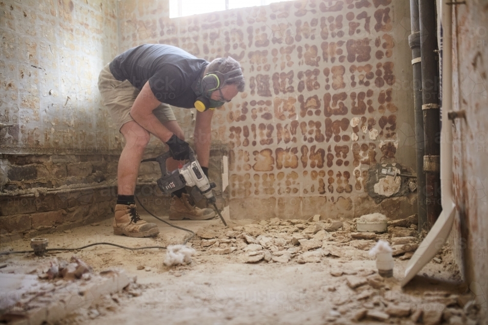 Tradesman jackhammering a floor in a construction site - Australian Stock Image