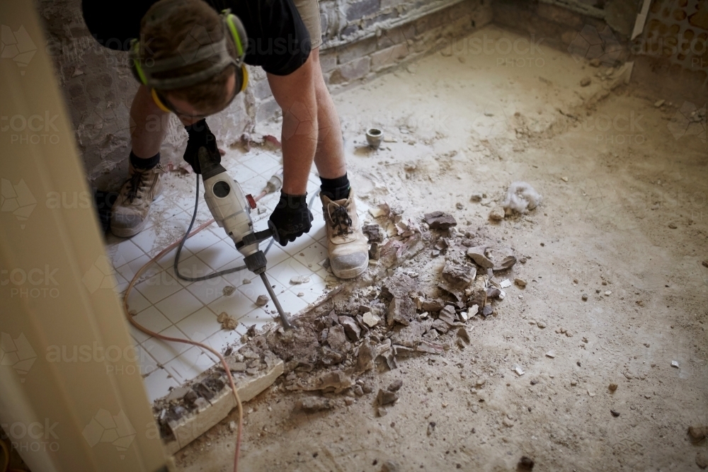 Tradesman jackhammering tiles on a worksite - Australian Stock Image