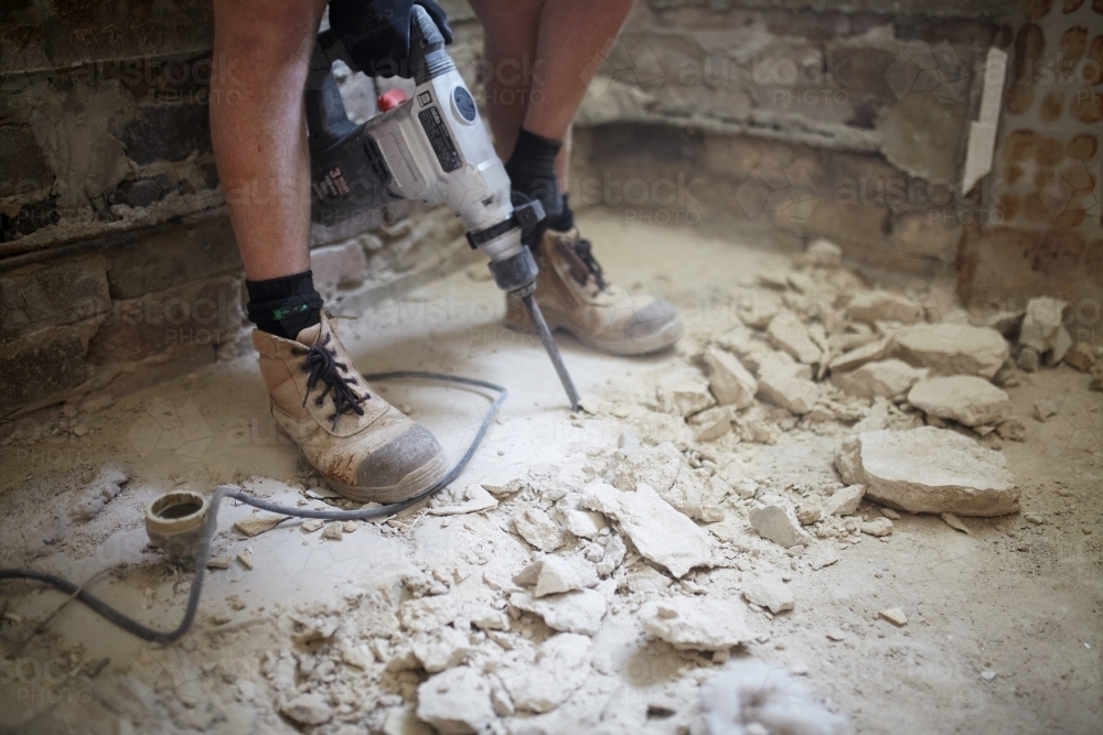 Tradie jackhammering a floor in a dusty worksite - Australian Stock Image