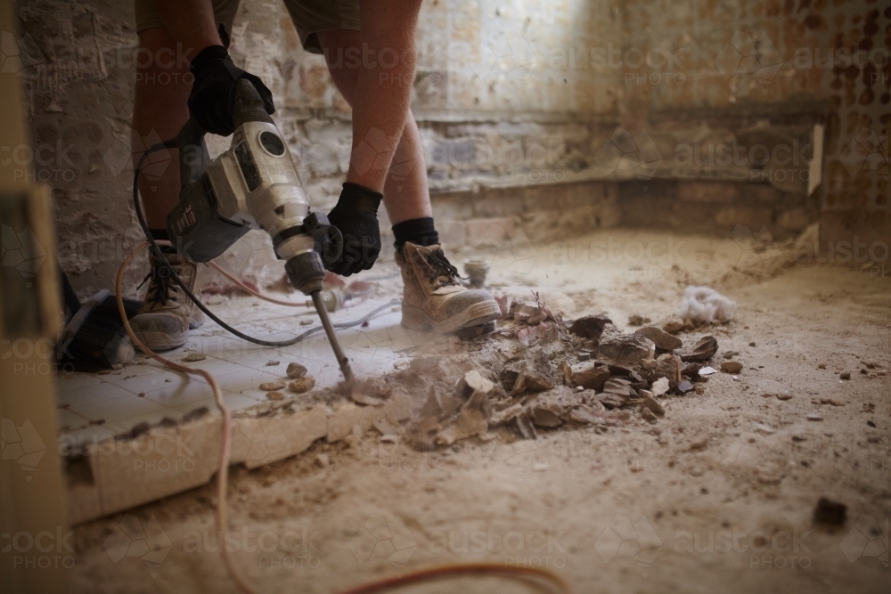 Tradie jackhammering a floor in a home renovation - Australian Stock Image