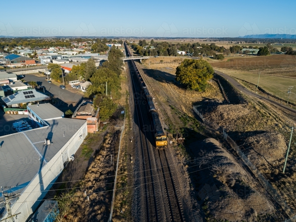 Train engine pulling empty coal train carriages along edge of country town - Australian Stock Image