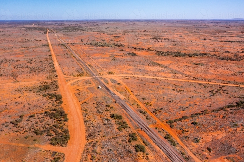 trans-Australian railway line stretching into distance in flat red dirt landscape central Australia - Australian Stock Image