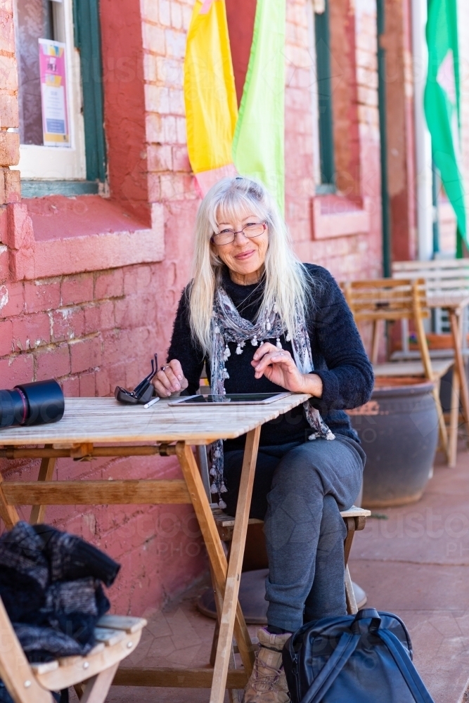 traveller sitting at table outside colourful building - Australian Stock Image