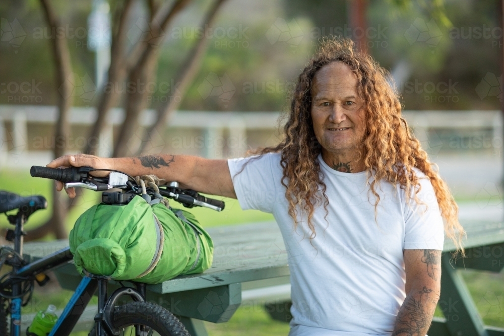 traveller sitting with bike in park - Australian Stock Image