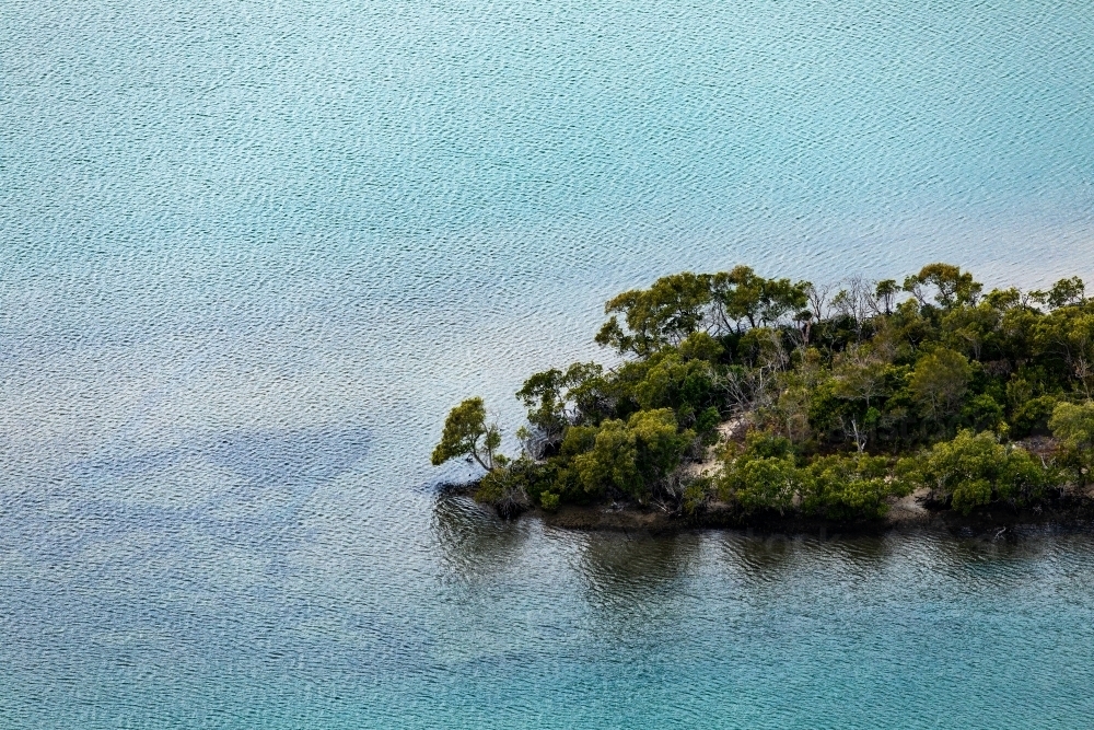 tree covered island in blue sea - Australian Stock Image