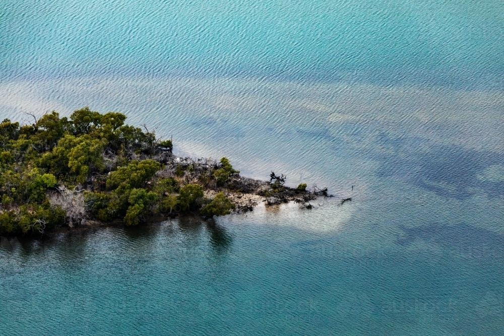 tree covered island in blue sea - Australian Stock Image