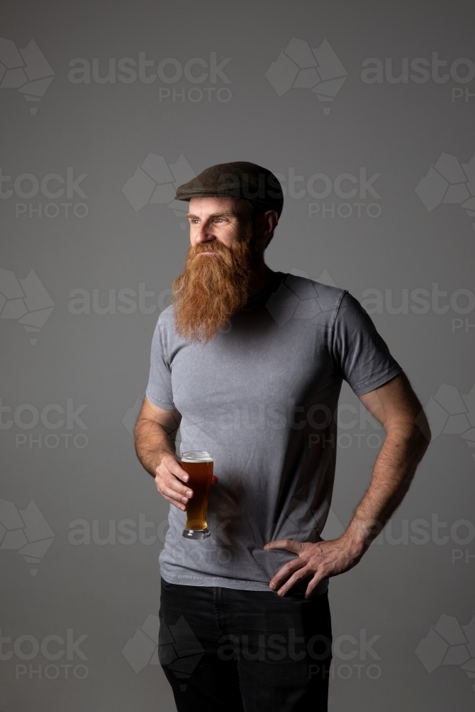 Trendy guy holding a glass of beer, relaxed and happy - Australian Stock Image